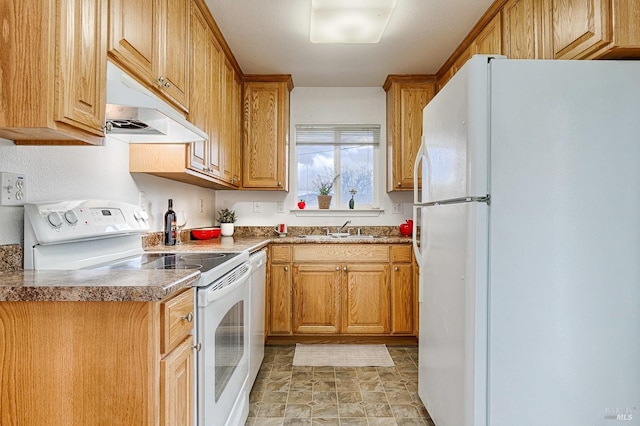 kitchen featuring white appliances, a sink, under cabinet range hood, stone finish flooring, and brown cabinets