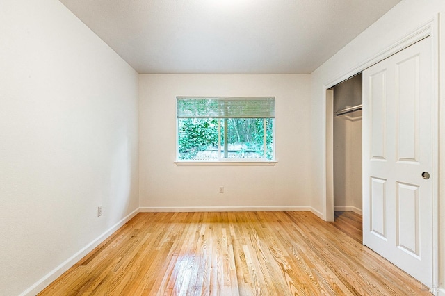 unfurnished bedroom featuring a closet, light wood-type flooring, and baseboards