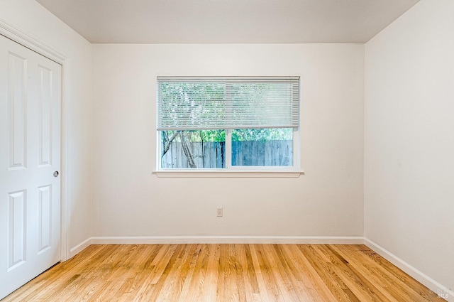 spare room featuring baseboards and light wood-style floors