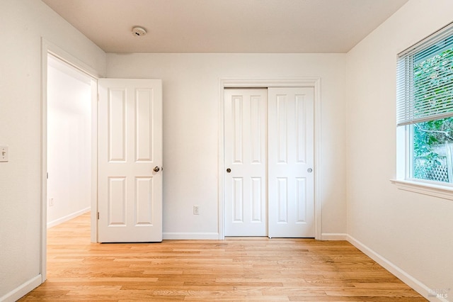 unfurnished bedroom featuring a closet, baseboards, and light wood-style flooring