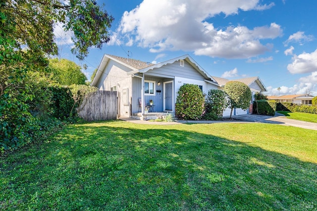 view of front of house featuring concrete driveway, a front yard, and fence