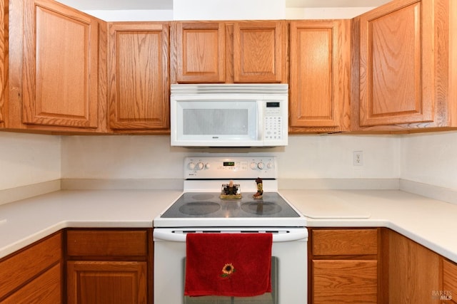 kitchen featuring built in desk, white appliances, and light countertops