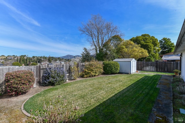 view of yard with a fenced backyard, a storage unit, and an outdoor structure