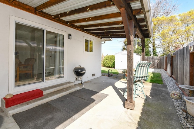 view of patio / terrace with an outdoor structure, a storage unit, and a fenced backyard