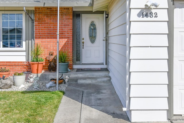 entrance to property featuring brick siding and roof with shingles