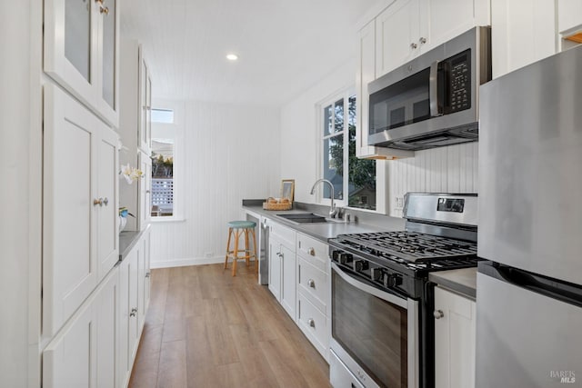 kitchen featuring white cabinetry, light wood-style floors, appliances with stainless steel finishes, and a sink