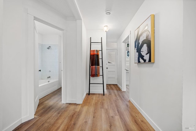 hallway featuring light wood-type flooring and baseboards