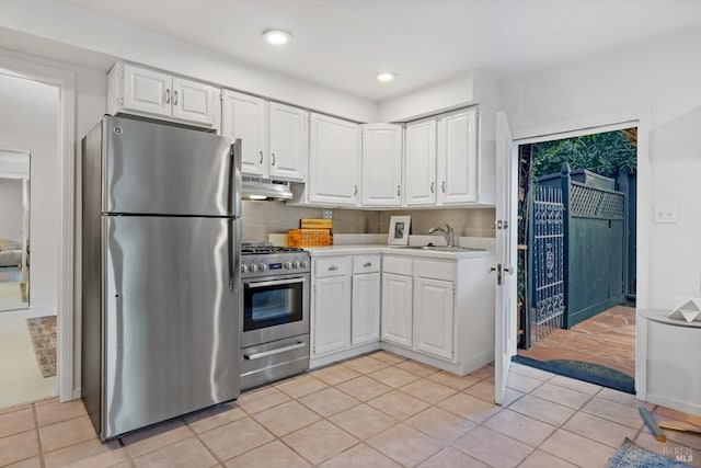 kitchen with under cabinet range hood, light countertops, stainless steel appliances, white cabinetry, and a sink