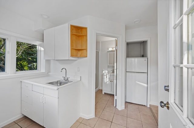 kitchen featuring a sink, freestanding refrigerator, light tile patterned flooring, white cabinets, and open shelves