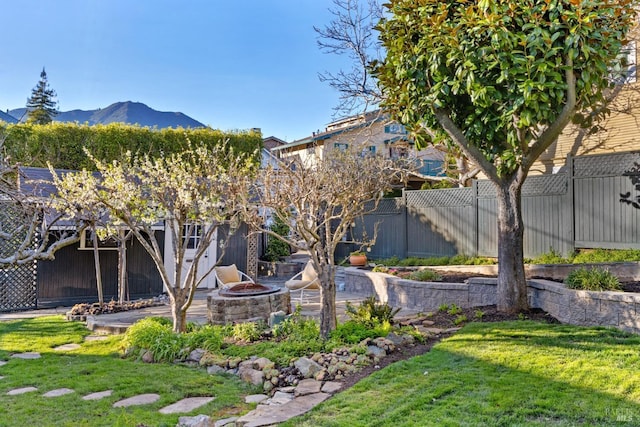 view of yard featuring a mountain view, a fire pit, a fenced backyard, and a patio