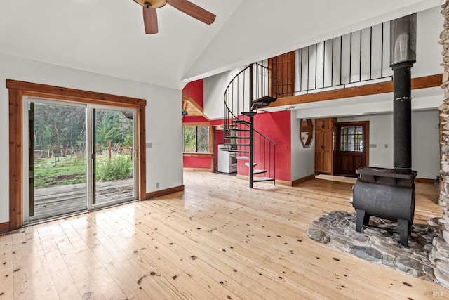 interior space with stairway, high vaulted ceiling, a wood stove, and hardwood / wood-style floors