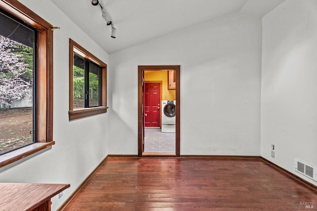 empty room with visible vents, washer / dryer, wood finished floors, and vaulted ceiling