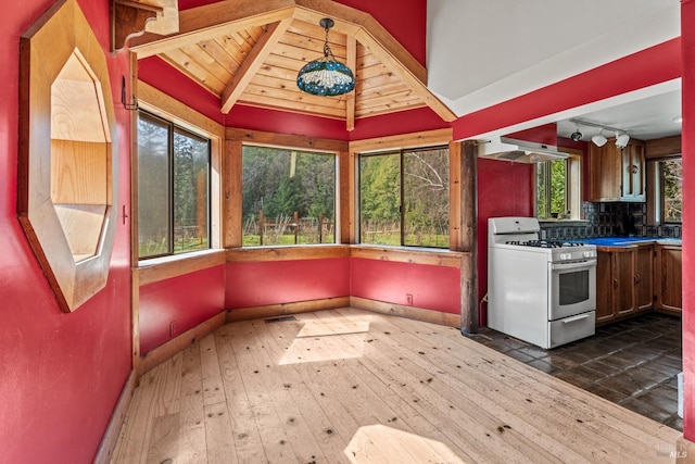 kitchen with lofted ceiling with beams, gas range gas stove, dark wood-style flooring, under cabinet range hood, and backsplash