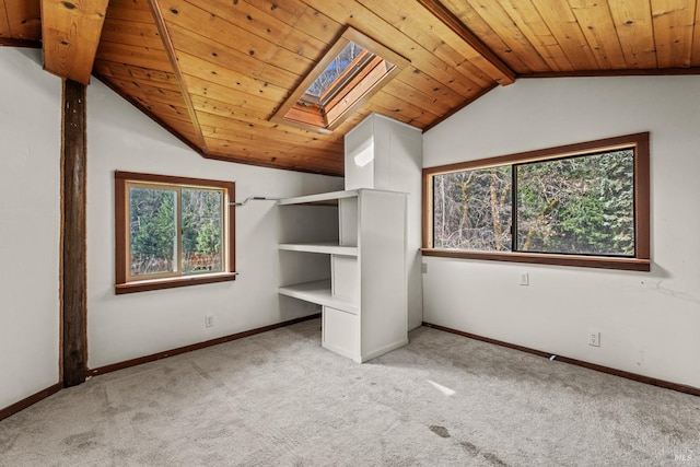 unfurnished bedroom featuring multiple windows, carpet floors, baseboards, and vaulted ceiling with skylight