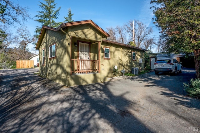 view of front of property with central AC unit, driveway, and fence