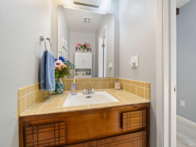 bathroom featuring vanity, decorative backsplash, and visible vents