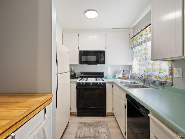 kitchen with black appliances, a sink, white cabinetry, light wood finished floors, and light countertops