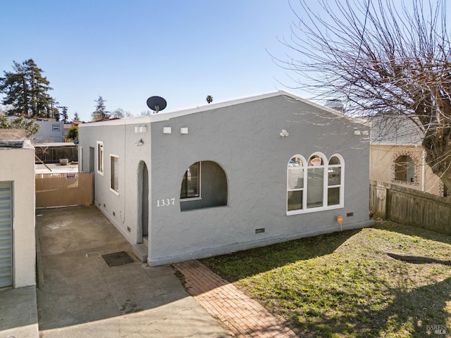 exterior space with crawl space, stucco siding, and fence