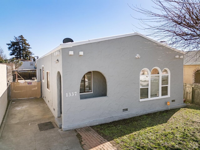 view of property exterior featuring crawl space, fence, and stucco siding