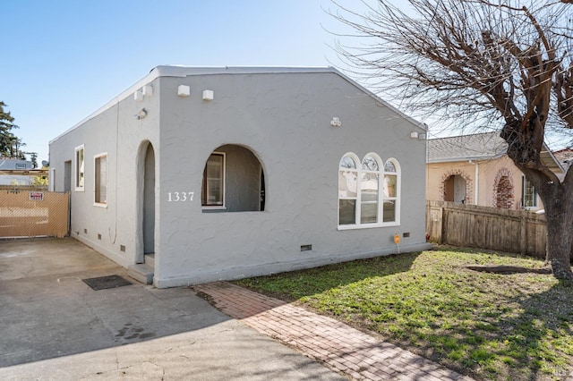 view of front of property with stucco siding, fence, a front yard, crawl space, and a patio area