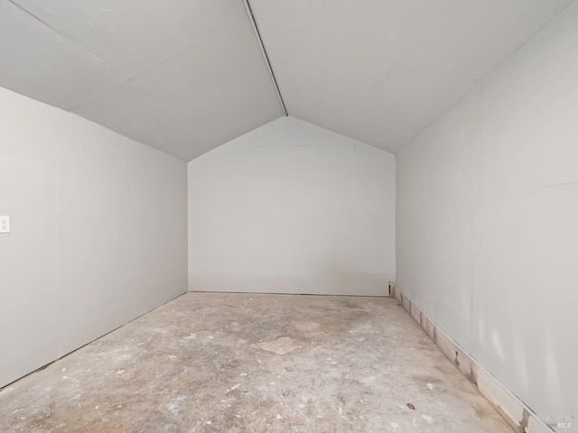 spare room featuring concrete flooring and vaulted ceiling