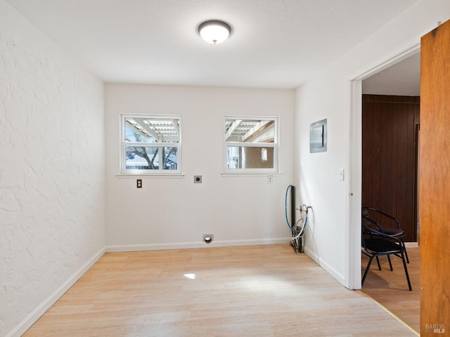 laundry room featuring electric dryer hookup, light wood-style floors, baseboards, laundry area, and a textured wall