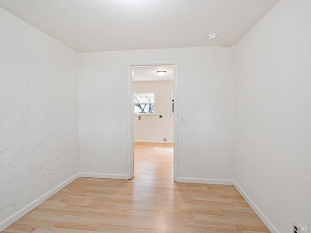 spare room featuring baseboards and light wood-type flooring