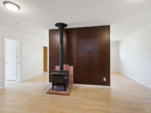 living area featuring a wood stove, wood finished floors, and baseboards