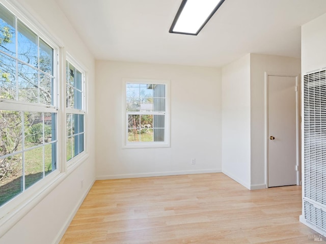 spare room featuring baseboards, light wood-style flooring, and a heating unit