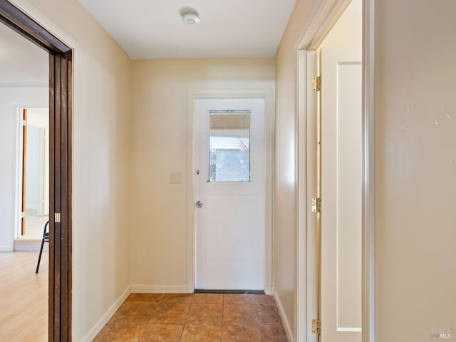 corridor featuring light tile patterned floors and baseboards