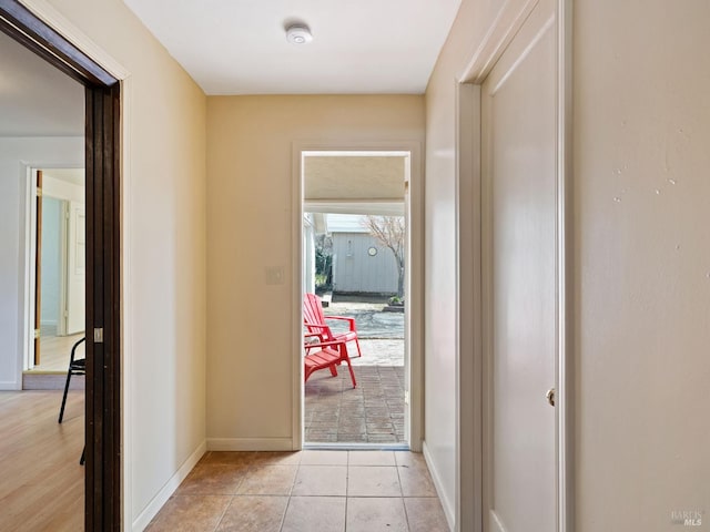 hallway featuring light tile patterned floors and baseboards