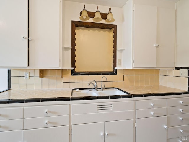 kitchen with white cabinetry, tasteful backsplash, and a sink