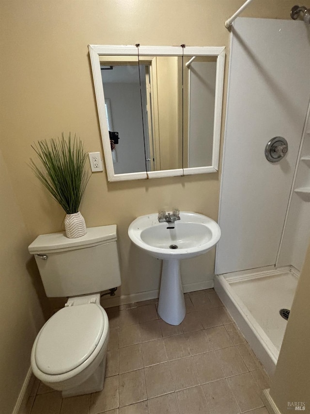 full bathroom featuring tile patterned floors, a stall shower, toilet, and baseboards