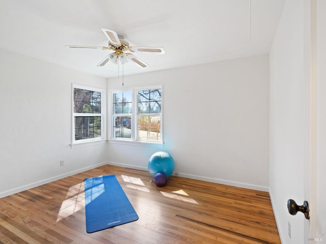 workout room featuring ceiling fan, baseboards, and wood finished floors