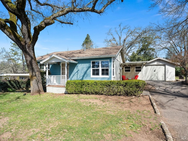 view of front facade featuring aphalt driveway, covered porch, and a front yard