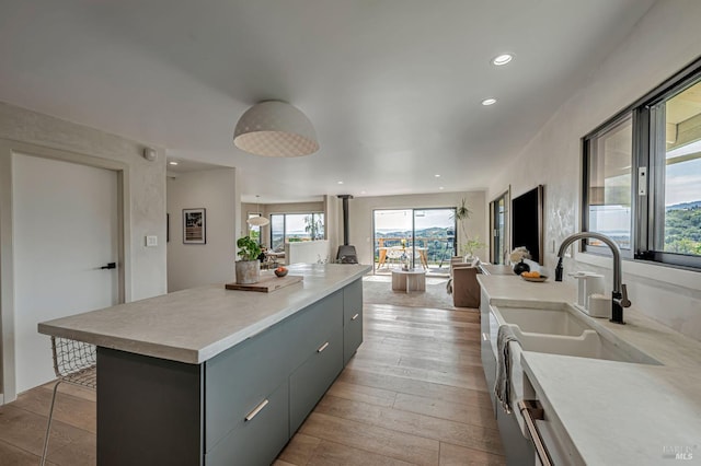 kitchen with gray cabinetry, a kitchen island, light countertops, recessed lighting, and light wood-style flooring