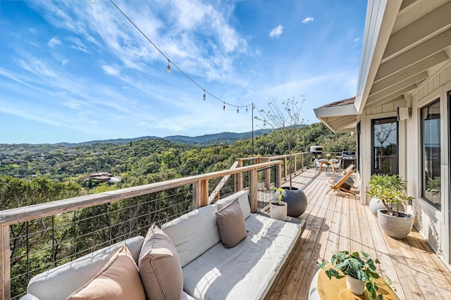 wooden deck with an outdoor living space, a mountain view, a wooded view, and a grill