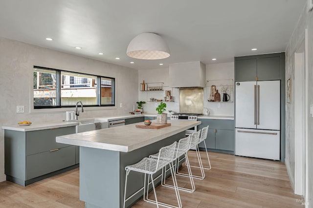 kitchen with light wood-style flooring, gray cabinetry, freestanding refrigerator, and a sink