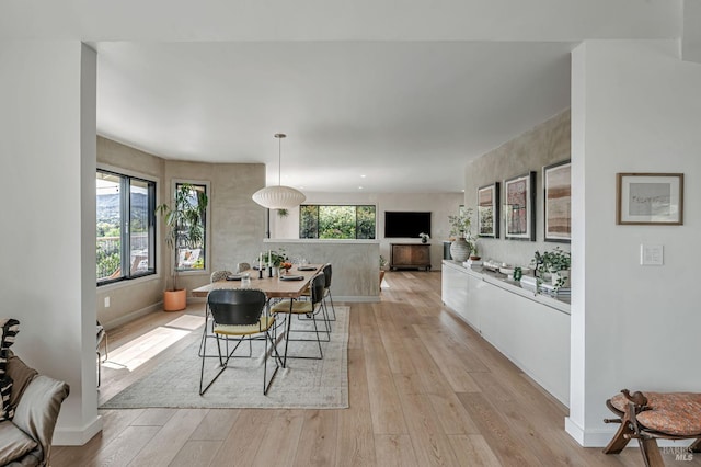 dining area featuring baseboards and light wood-style flooring