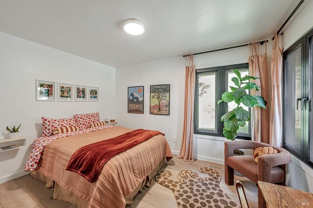 bedroom featuring baseboards, light wood-style flooring, and access to exterior