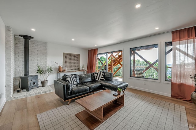 living room with recessed lighting, baseboards, wood finished floors, and a wood stove