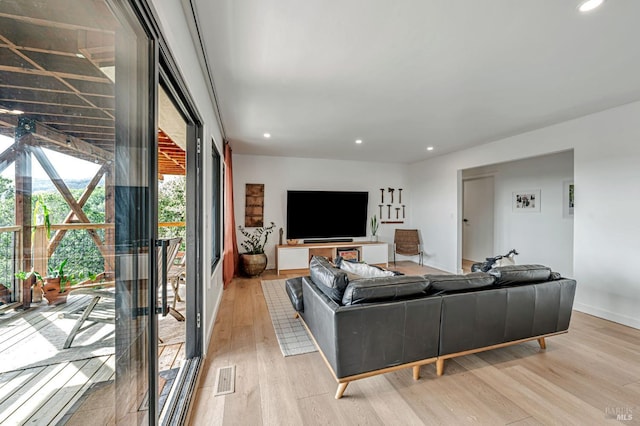 living area with recessed lighting, visible vents, light wood finished floors, and baseboards