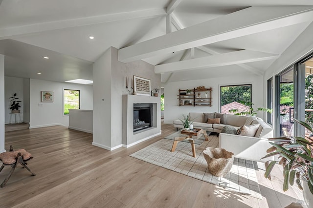 living room featuring light wood-style flooring, plenty of natural light, baseboards, and vaulted ceiling with beams