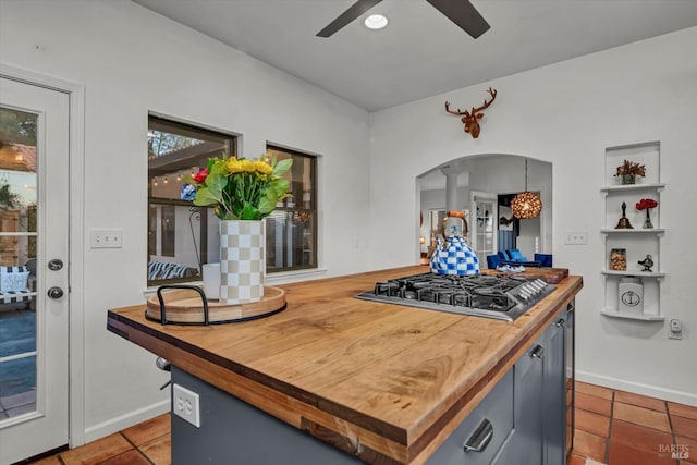 kitchen featuring tile patterned flooring, wooden counters, ceiling fan, stainless steel gas cooktop, and arched walkways