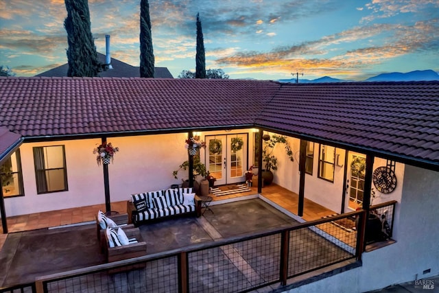 rear view of house featuring french doors, a patio area, stucco siding, and a tile roof