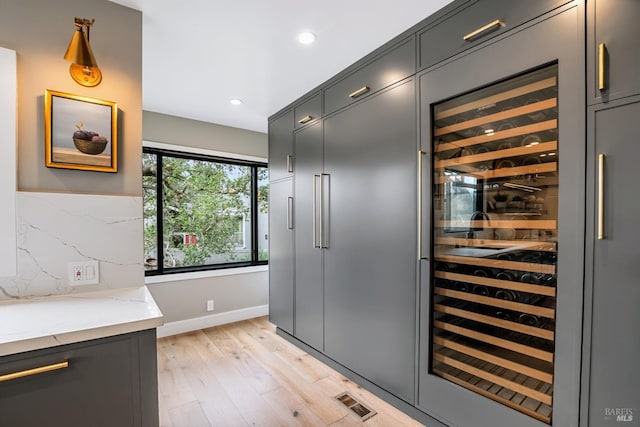 interior space featuring light wood-type flooring, beverage cooler, recessed lighting, decorative backsplash, and baseboards