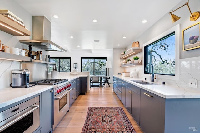 kitchen with open shelves, ventilation hood, appliances with stainless steel finishes, and a sink