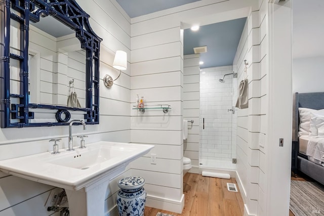 ensuite bathroom with visible vents, toilet, a stall shower, ensuite bathroom, and wood finished floors