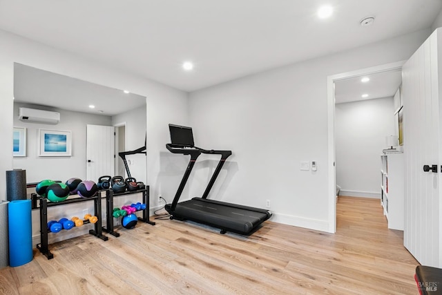 exercise area with recessed lighting, a wall mounted air conditioner, baseboards, and wood finished floors