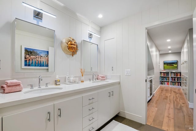 bathroom with a sink, wood finished floors, and double vanity